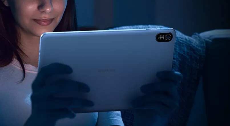 Una donna sorridente utilizza un tablet Blackview di notte.